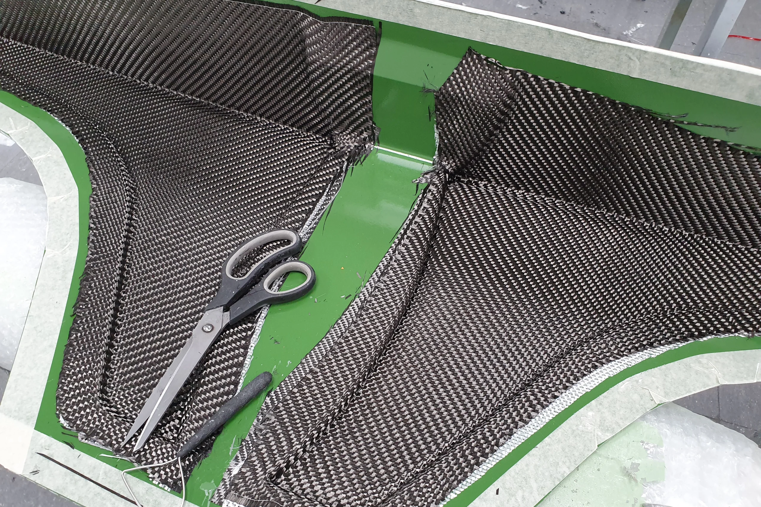 Stesura di tessuto in fibra di carbonio in uno stampo composito, a dimostrazione dei processi avanzati di lavorazione e ingegnerizzazione.